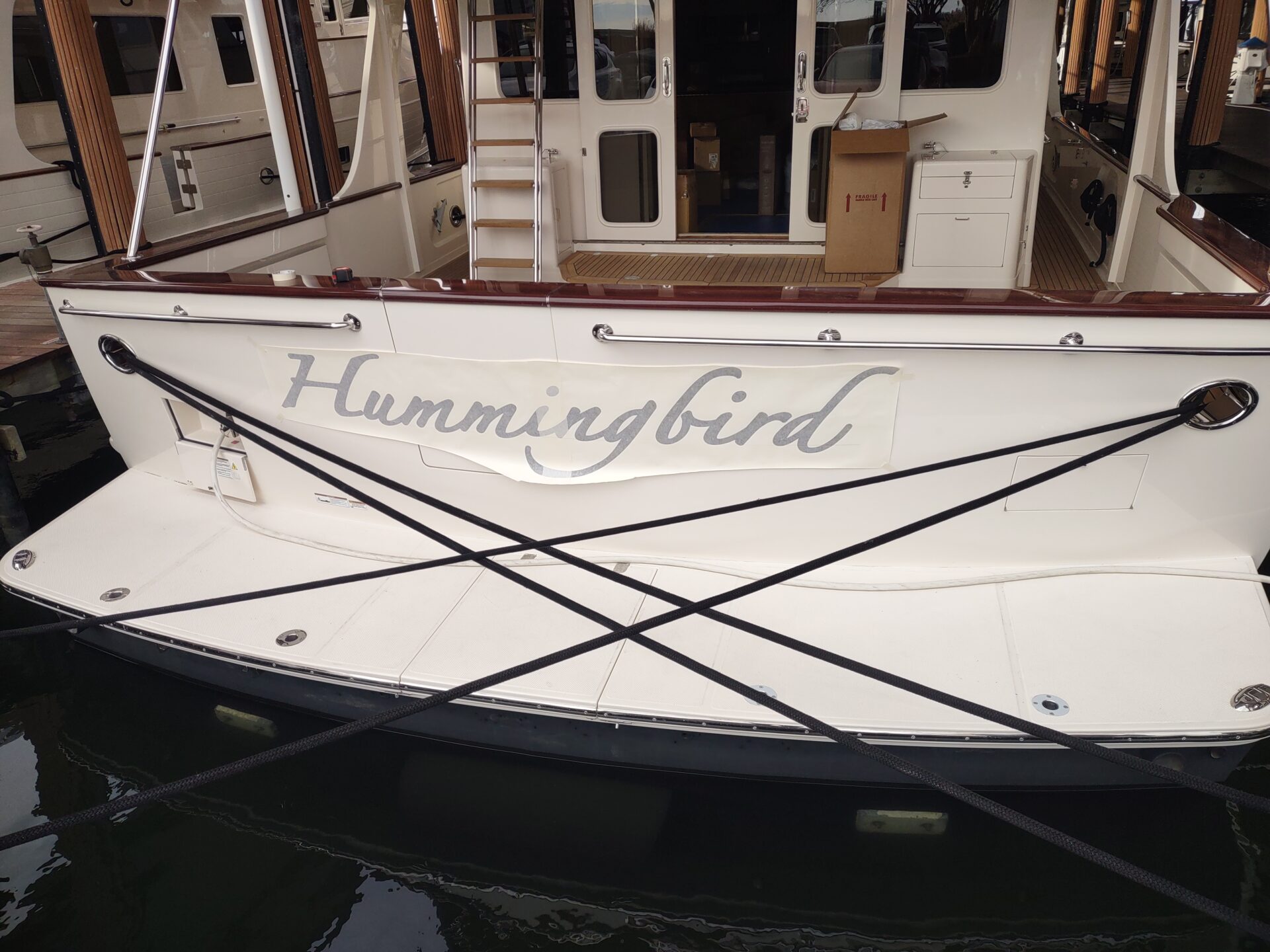 black Avery vinyl layer for the Hummingbird script boat name taped into position with the application mask still on