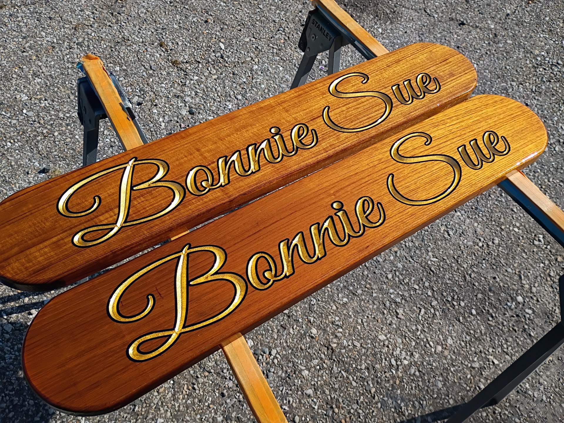 Pair of carved teak quarterboards reading Bonnie Sue in gold leaf script with a black outline
