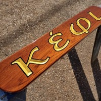 A teak board with carved letters and gold leaf.